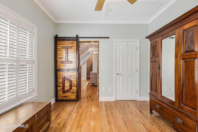 unfurnished bedroom with crown molding, a barn door, light hardwood / wood-style flooring, and ceiling fan