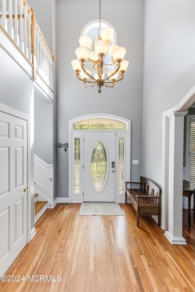 foyer entrance featuring light hardwood / wood-style flooring, a chandelier, and a high ceiling