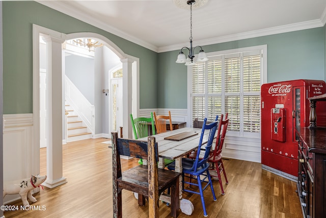 dining room with crown molding, hardwood / wood-style flooring, decorative columns, and an inviting chandelier