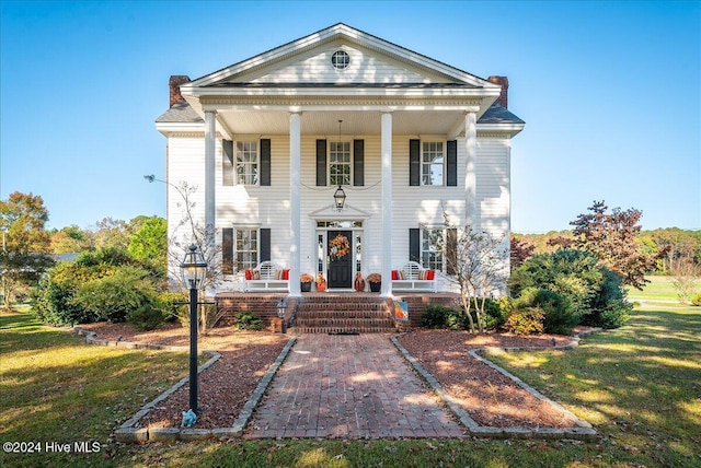 greek revival house with a front lawn and covered porch