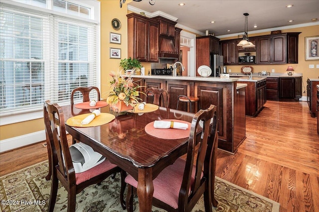 dining room with ornamental molding, light hardwood / wood-style floors, and sink