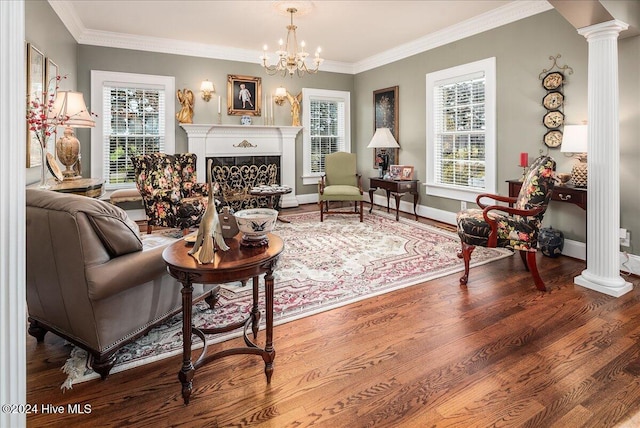 living area featuring hardwood / wood-style floors, a wealth of natural light, crown molding, and decorative columns