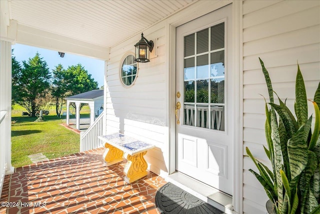 doorway to property with a porch and a lawn