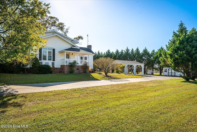 view of front of property featuring a front lawn, a shed, and a porch