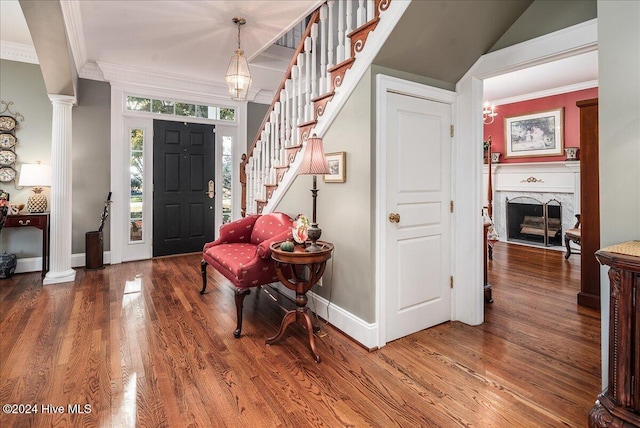 entryway with hardwood / wood-style flooring, crown molding, and decorative columns