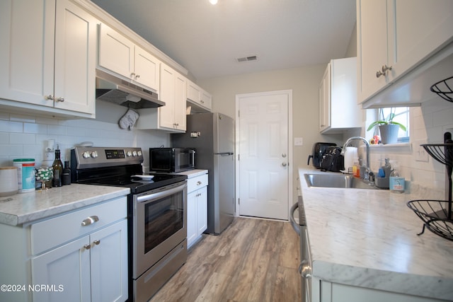 kitchen with light hardwood / wood-style floors, decorative backsplash, sink, stainless steel appliances, and white cabinets