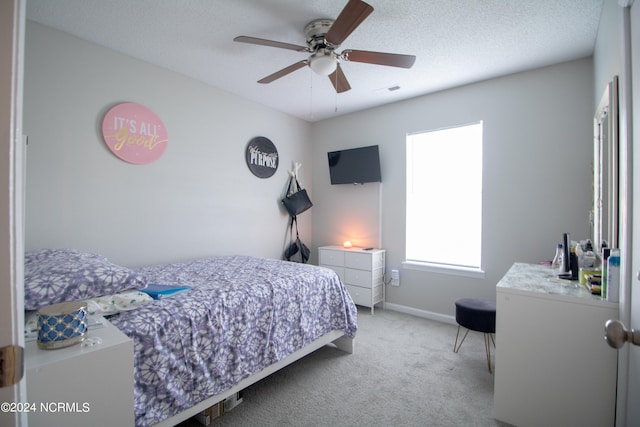 carpeted bedroom with ceiling fan and a textured ceiling