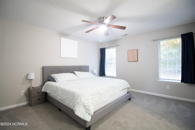 carpeted bedroom featuring ceiling fan and a textured ceiling