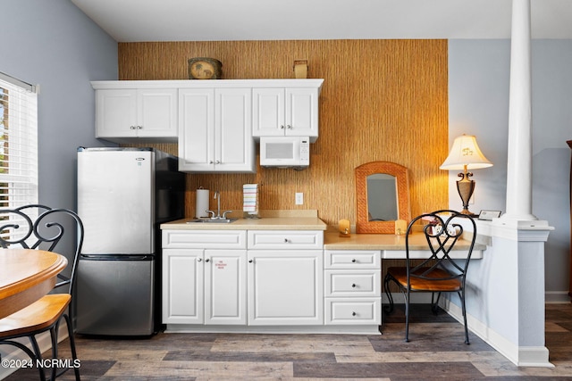 kitchen featuring stainless steel fridge, white cabinetry, wood walls, and dark hardwood / wood-style floors