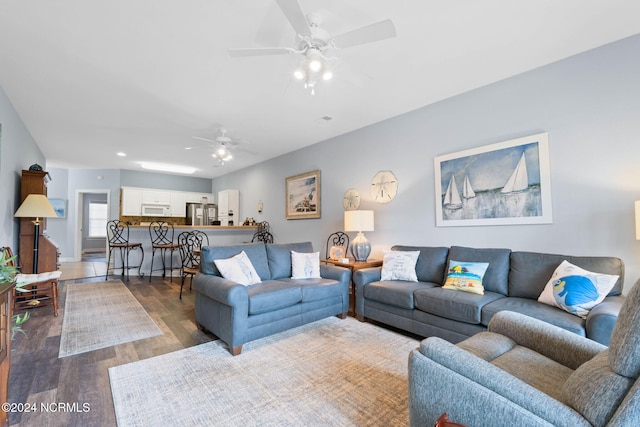 living room featuring ceiling fan and dark hardwood / wood-style floors