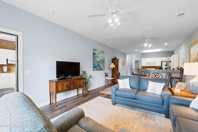 living room featuring ceiling fan and dark hardwood / wood-style floors