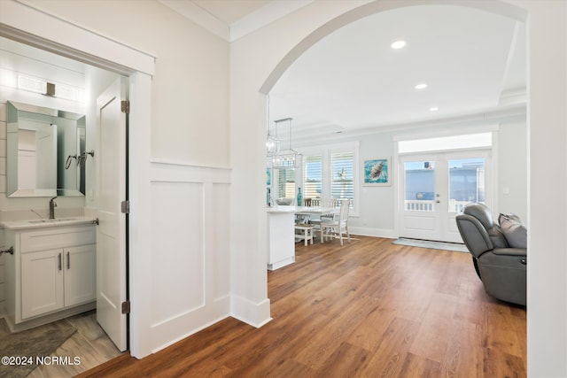 hallway featuring crown molding, recessed lighting, wood finished floors, arched walkways, and a sink