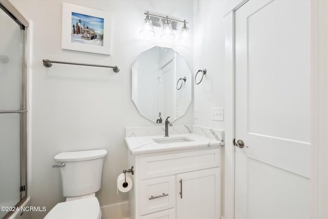 bathroom with toilet, an enclosed shower, and vanity