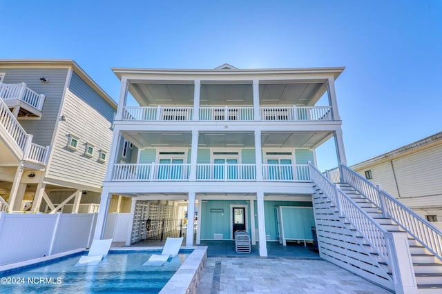 rear view of house with fence, stairway, a fenced in pool, a carport, and a patio area