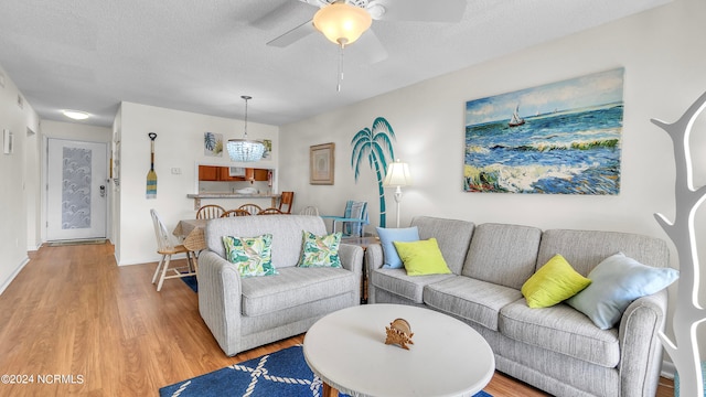 living room featuring ceiling fan, light hardwood / wood-style floors, and a textured ceiling