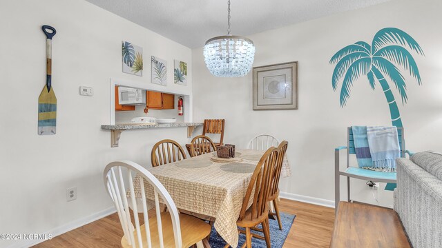 dining space featuring baseboards, a notable chandelier, and light wood-style flooring