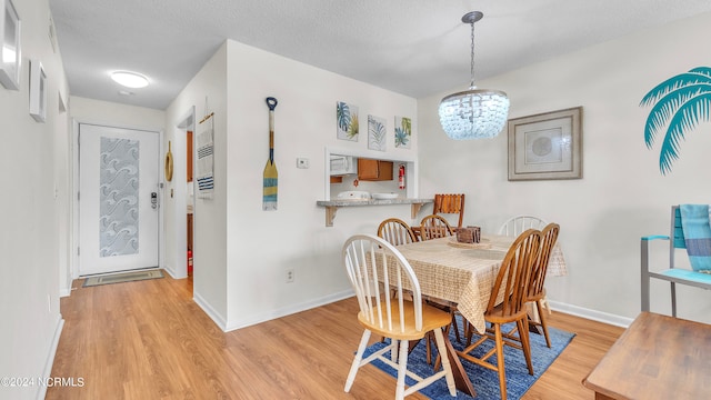 dining room featuring a chandelier, light hardwood / wood-style floors, and a textured ceiling