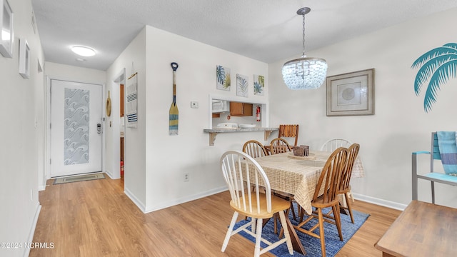 dining space with baseboards, a chandelier, and light wood finished floors