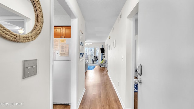 hall featuring baseboards, visible vents, and light wood-style flooring