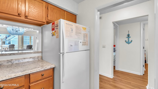 kitchen featuring white fridge, a chandelier, and light hardwood / wood-style floors