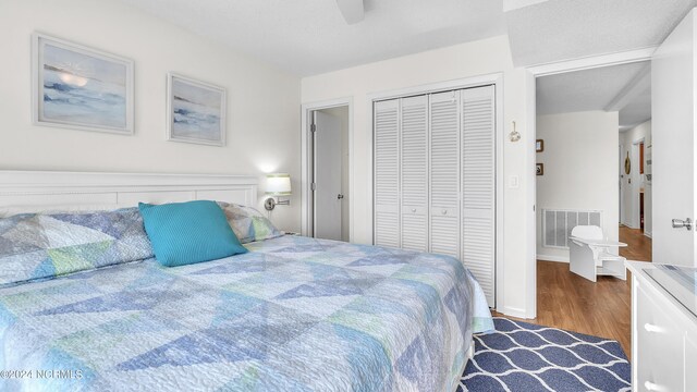 bedroom featuring visible vents, a closet, wood finished floors, baseboards, and ceiling fan