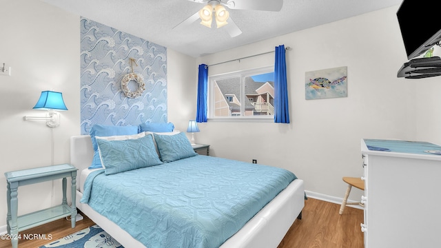 bedroom featuring baseboards, a textured ceiling, ceiling fan, and wood finished floors