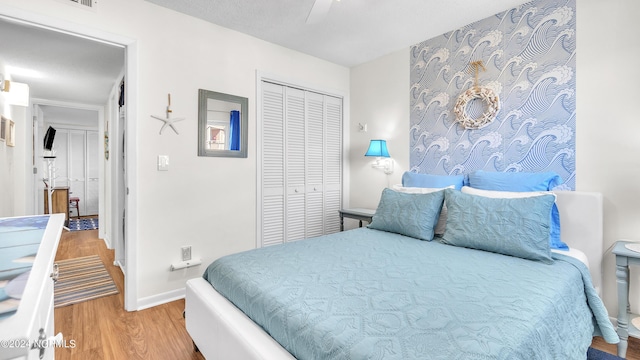 bedroom with baseboards, ceiling fan, wood finished floors, and a closet