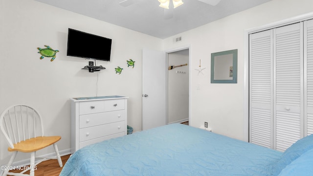 bedroom with ceiling fan, baseboards, wood finished floors, visible vents, and a closet