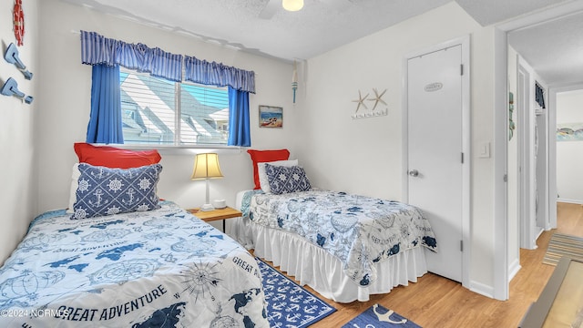 bedroom with a textured ceiling, ceiling fan, and wood finished floors