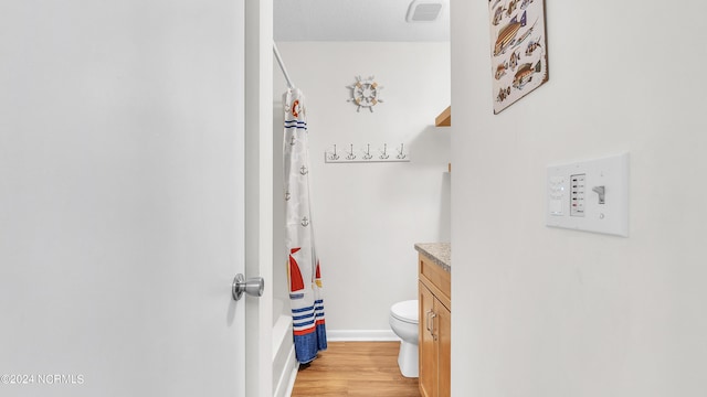 bathroom featuring vanity, visible vents, wood finished floors, toilet, and baseboards