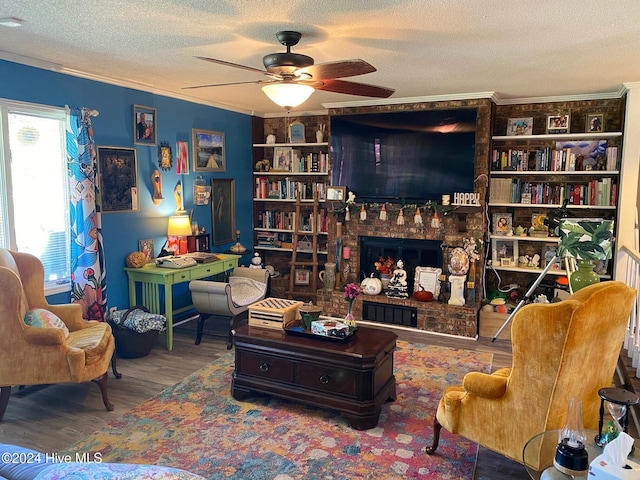 living area with ceiling fan, crown molding, hardwood / wood-style floors, a textured ceiling, and a fireplace