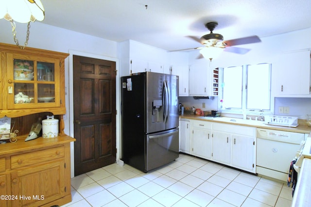 kitchen with white cabinets, sink, ceiling fan, stainless steel fridge, and light tile patterned flooring