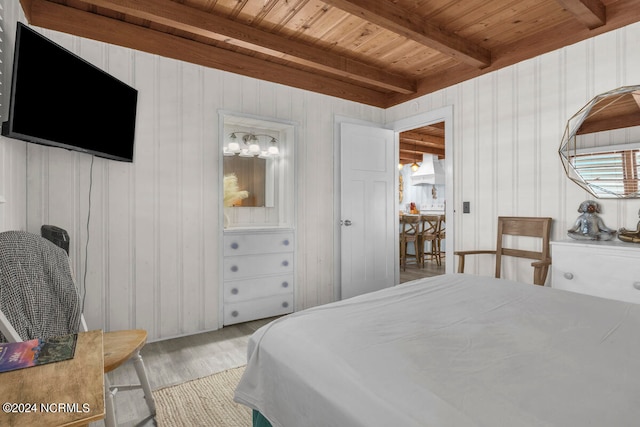 bedroom featuring light hardwood / wood-style flooring, beam ceiling, and multiple windows