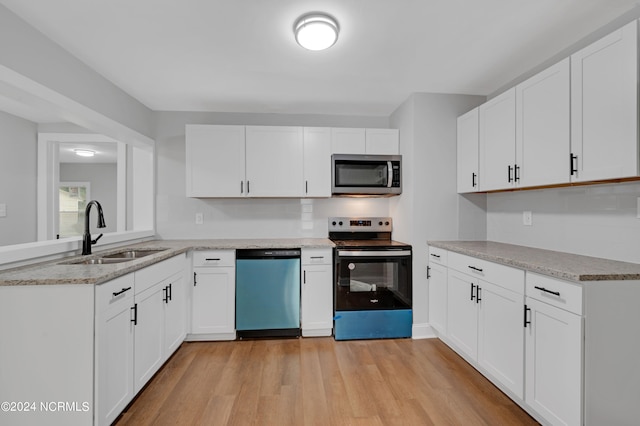 kitchen with white cabinets, stainless steel appliances, light wood-type flooring, and sink