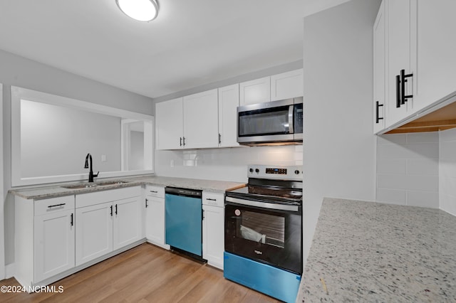 kitchen with light wood-type flooring, sink, backsplash, appliances with stainless steel finishes, and white cabinetry