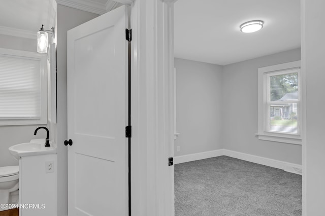 bathroom featuring a sink, baseboards, ornamental molding, and toilet