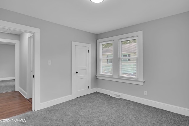 empty room featuring baseboards, dark carpet, and visible vents
