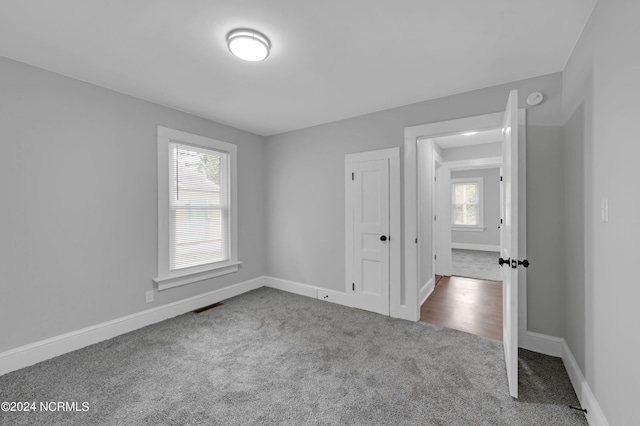 unfurnished bedroom with carpet floors, baseboards, visible vents, and multiple windows
