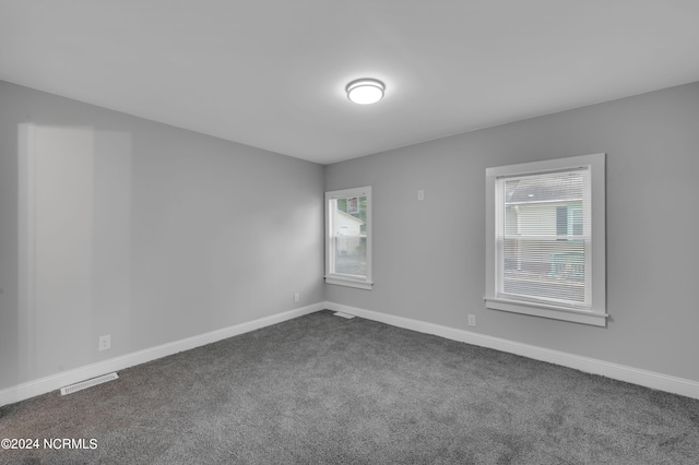 unfurnished room featuring baseboards, visible vents, and dark colored carpet