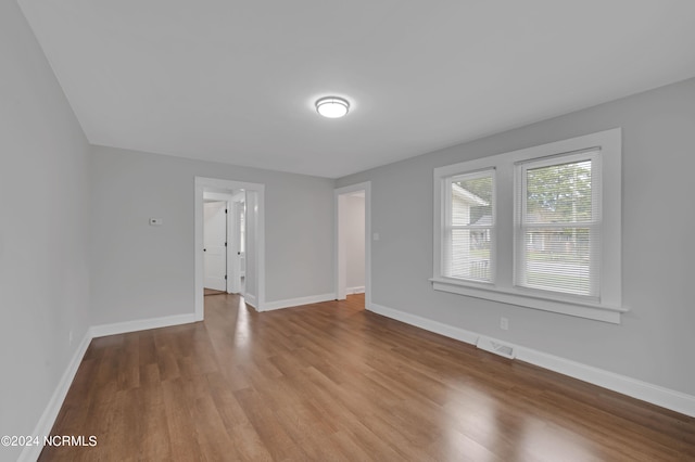 unfurnished room featuring visible vents, baseboards, and wood finished floors
