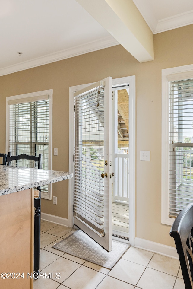 doorway featuring crown molding, a healthy amount of sunlight, and light tile patterned floors