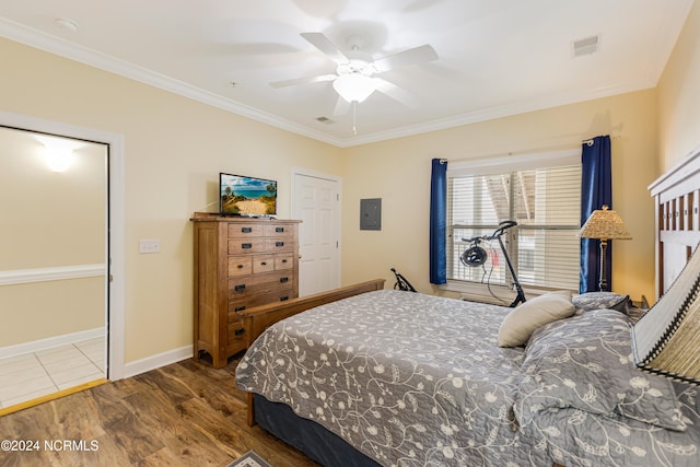 bedroom with ornamental molding, electric panel, wood-type flooring, and ceiling fan