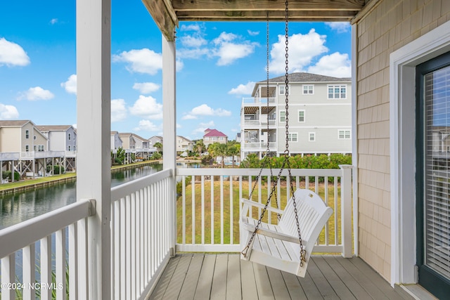 wooden deck featuring a water view and a lawn