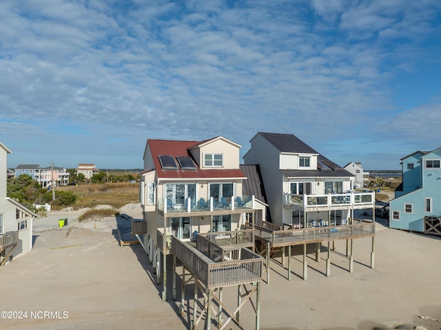 rear view of property with a standing seam roof, metal roof, and roof mounted solar panels