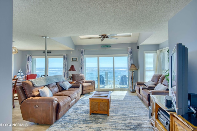 living room featuring light hardwood / wood-style floors, a healthy amount of sunlight, a textured ceiling, and ceiling fan