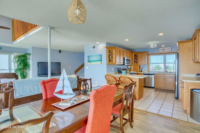 dining room featuring sink, a textured ceiling, and light hardwood / wood-style flooring