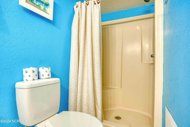 bathroom featuring toilet, a textured ceiling, and a shower with shower curtain