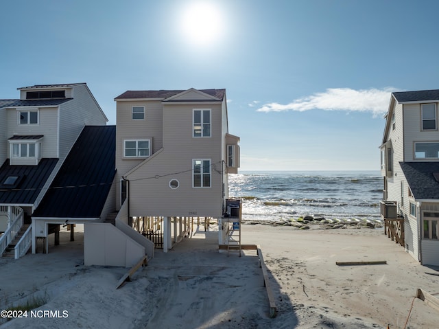 rear view of property with a water view and a beach view