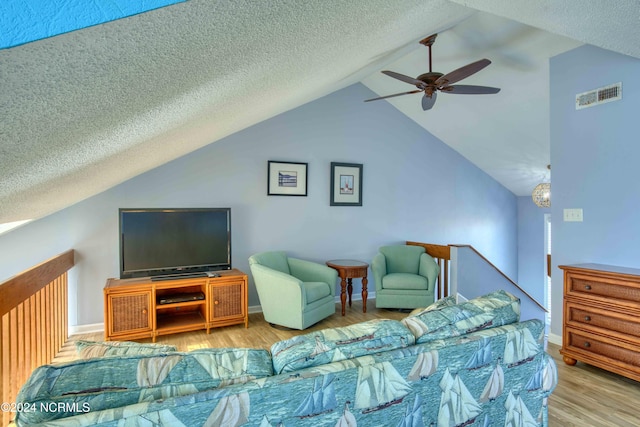 living room with light hardwood / wood-style floors, lofted ceiling, a textured ceiling, and ceiling fan