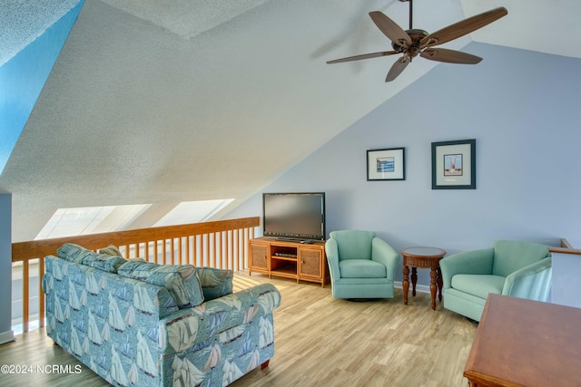 living room featuring vaulted ceiling, light hardwood / wood-style flooring, a textured ceiling, and ceiling fan